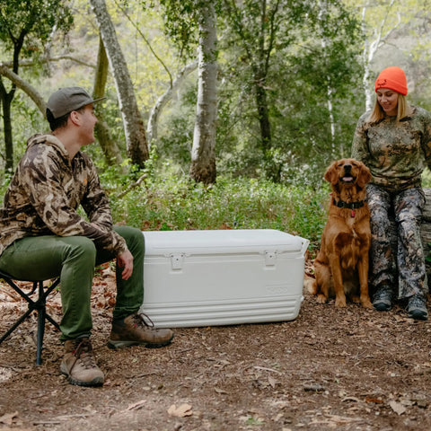 Beast Mode Heavy Duty 120 Qt Polar Cooler With UV Shield Lid in outdoor setting with people in camo and dog.