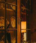 Glass cabinet door showcasing china plates with classic latch hardware