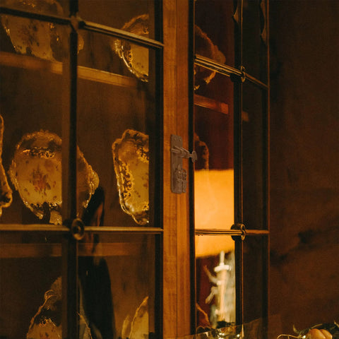 Glass cabinet door showcasing china plates with classic latch hardware