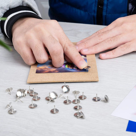 Person using Real Solid Silver Flat Head Thumb Tacks And Push Pins With Slick Low Profile Design for crafts on a board.