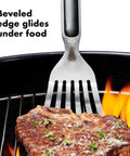 Grilling Tool Precision Turner For Effortless Burger Flips And Flaky Fish Fillets With Thin Beveled Head Non Slip Grip And Hanging Ring OXO Good Grips Black lifting steak on grill