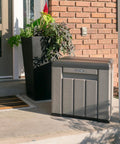 Versatile Outdoor Storage Cube Deck Box Doubles As Cozy Bench Seat And 25 Gallon Capacity Weather Resistant Patio Organizer near a front door.