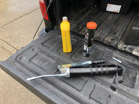 Heavy Duty Lever Grease Gun That Feels Like A Beast, 10,000 PSI Power, painted steel barrel with oversized grip on a truck bed