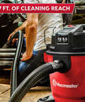 Heavy Duty 12 Gal Wet Dry Shop Vac With Beastly 5.5 Peak HP Motor And Nine Must Have Cleaning Attachments For Cranking Nasty Garage Jobs And Spills Features Classic Red Plastic Design, shown in use with a long hose.