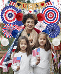 Patriotic Decorations Bundle for Veterans Day and Fourth of July with paper fans, poms, USA flags, Love USA banner, outdoors