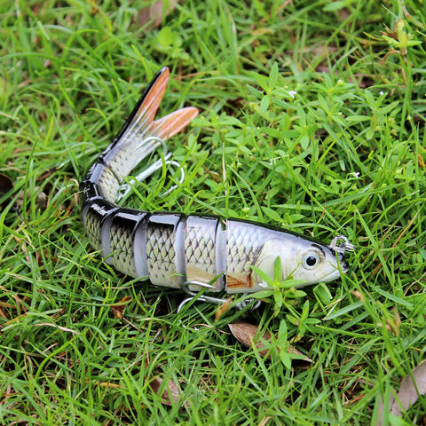Easy Catch Three Action Swimbait Lure With BKK Hooks on grass, showcasing jointed body and realistic design for multiple fish types.