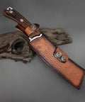 Beefy Dual Purpose Kitchen And Outdoor Cleaver For Bone Chopping And Bushcraft Wood Splitting in leather sheath on wood surface.