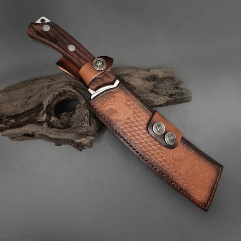 Beefy Dual Purpose Kitchen And Outdoor Cleaver For Bone Chopping And Bushcraft Wood Splitting in leather sheath on wood surface.