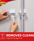 Smooth Broom And Mop Gripper Organizer With Adhesive Strips For Damage Free Hanging Holds Up To Four Pounds For Handles Ranging From Point Eight To One Inch Handy Home Cleanup Solution being used on a wall to hold a handle securely.