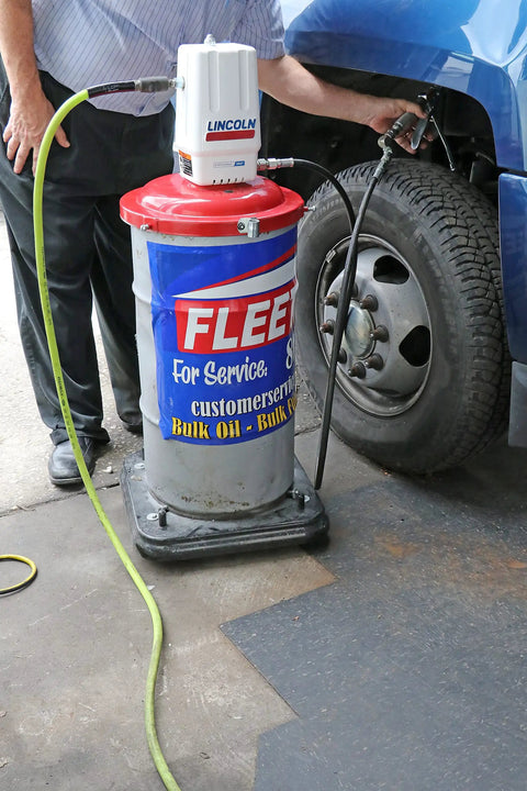 Lincoln 917 Pro Grade 50 To 1 Pneumatic Grease Pump in use with 120 lb drum next to a truck tire