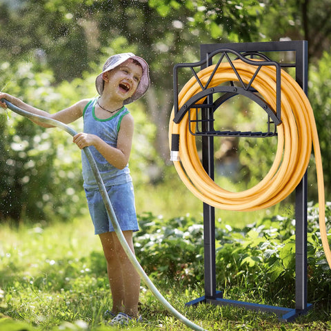 Heavy Duty Outdoor Garden Hose Holder With 5 Spikes And Basket in use, child playing with hose, freestanding black metal stand