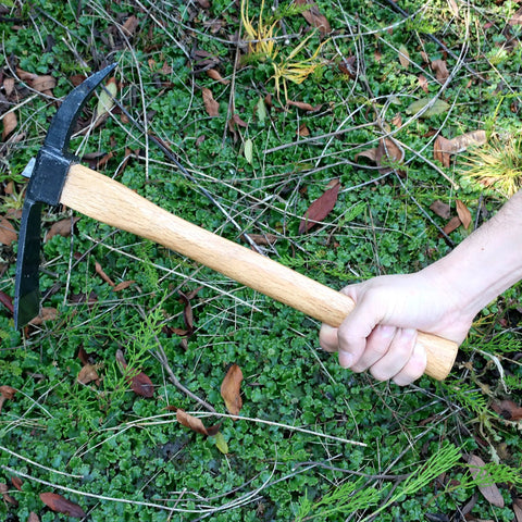Hand holding Beast Of A Heavy Duty Japanese Hand Forged Steel Pick Axe For Digging And Weeding Gardens, 14-3/4 inch mattock tool.