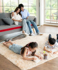 Family relaxing on sofa and children drawing on plush carpet with visible hardwood flooring.