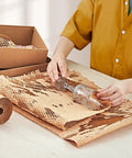Person wrapping glass vase in Honeycomb Packing Paper Roll 15 Inch By 400 Feet Expands Up To 640 Feet Cushioning Wrap