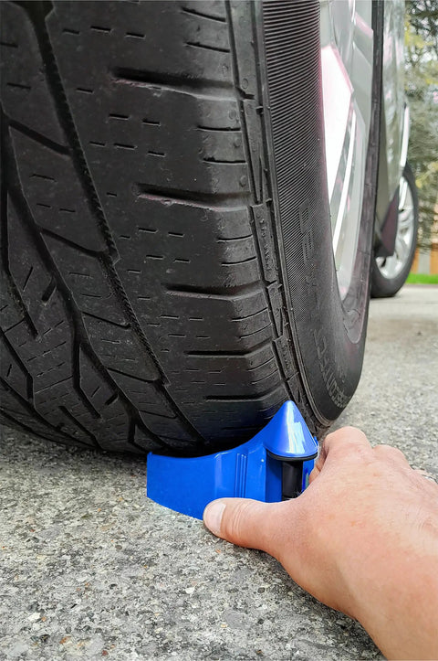Hand placing Blue Car Hose Guides Two Pack With Patented Roller System And Active Locking Grips under tire, fits any size.