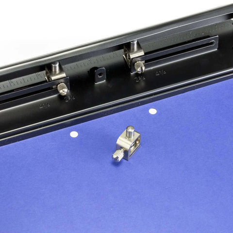 Close-up of adjustable three-hole punch for office documents with 11 sheet capacity, showing blue paper and black metal punch tool.
