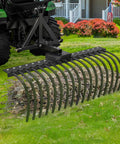 Beast Of A Tow Behind Landscape Rake For ATV And UTV 48 Inch Wide With 2 Inch Receiver 17 Heavy Duty Spring Steel Tines Lawn Dethatcher Attachment For Leaves Debris And Grass Powder Coated Alloy Steel Black shown attached to ATV.