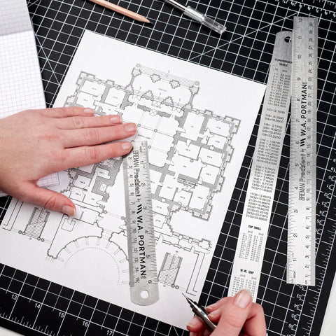 Close-up of Stainless Steel Ruler Set Three Pack With One 6 Inch And Two 12 Inch Metal Straight Edges for precise drawing on blueprint.
