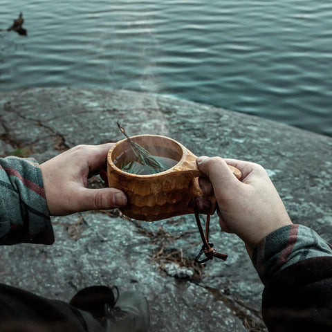 Person holding Kuksa Wooden Cup Handcarved 8 Oz Coffee Mug With Lanyard And Carabiner For Camping Outdoors by a lake