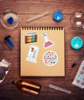 Notebook with 110 Piece Science Stickers Pack For Chemistry Biology Physics Fans, featuring vinyl decals and lab tools.