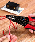 Person using All In One Wire Stripper And Cable Splicer Tool For 10 22 AWG on red wire, showing ergonomic TPR handles and markings.