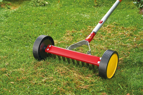 Multi-Change Roller Moss Removal Rake Tool Head For Lawn Care And Thatch Removal on grass, red wheel-driven rake attachment