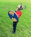 Child wearing Kids Viking Horned Helmet For Costume Play LARP And Halloween holding shield outdoors