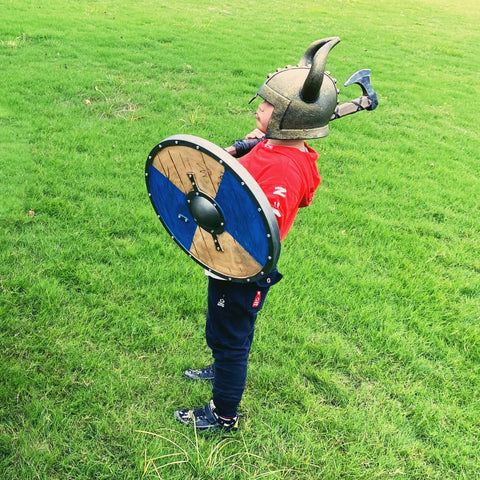 Child wearing Kids Viking Horned Helmet For Costume Play LARP And Halloween holding shield outdoors