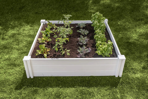 White Vinyl Raised Garden Bed 4 Ft By 4 Ft By 11 In Deep with Modular PVC Construction shown installed on grass with plants.