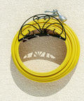 Heavy Duty Metal Hose Holder Wall Mount For Outdoor Yard Solid Iron Garden Hose Reel Organizer Waterproof Powder Coated Rustproof Storage Hanger For Easy Access And Clean Durable Outdoor Hose Management showing yellow hose on cream wall