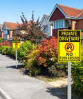 Set of two 14x10 inch aluminum driveway signs, yellow with black text, on long stakes in a suburban street scene