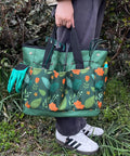 Person holding a green floral Waterproof Garden Tool Bag With 8 Side Pockets And Big Main Compartment, Durable 600D Oxford Tote.