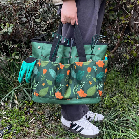 Person holding a green floral Waterproof Garden Tool Bag With 8 Side Pockets And Big Main Compartment, Durable 600D Oxford Tote.
