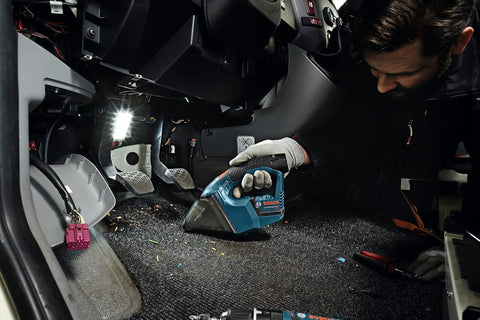 Person using a 12V Max Hand Vacuum Bare Tool for quick jobsite cleanup with ultra lightweight design, high power suction on car floor.