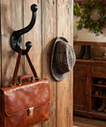 Six Pack Cast Iron Wall Hooks Vintage Black Metal Heavy Duty Coat Rack hanging a leather bag and hats in rustic decor.