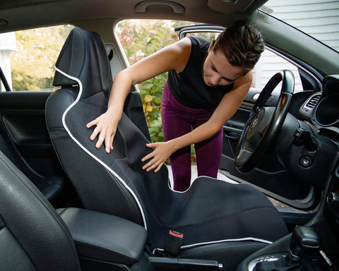 Person adjusting Go-To Universal Fit Waterproof Car Seat Cover With Neoprene, Stain-Resistant, Non-Slip Bucket Seat Protector in a car.