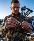 Hunter inserting Brass Arrow Inserts 6.2mm.244 ID into carbon arrow during snowy mountain hunt