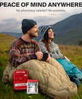 SurviveX travel first aid kit in red pouch with white TravelRx packet outdoors beside campers