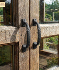 Twisted Grip Mystic Colonial Rustic 6.5 Inch Barn Door Handle Pull for Sliding Barn Doors in black wrought iron on a wooden gate.