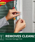 Person attaching Outdoor Small Refill Adhesive Strips Pack With 16 Strips For Rehang Outdoor Window Hooks on window frame