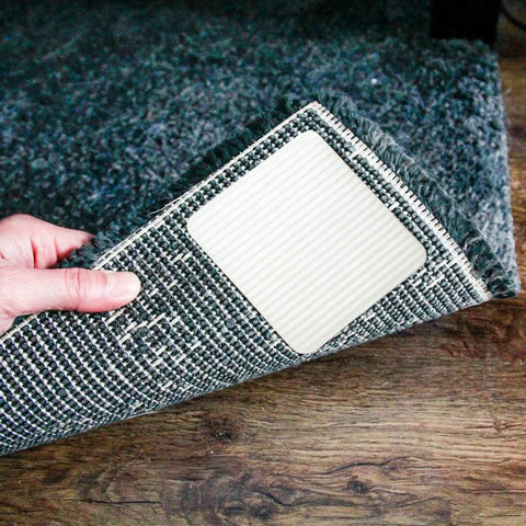 Close-up of 4 Pack Extra Strong Non Slip Rug Pad Tape With Vacuum Tech Grip for Hardwood Floors being applied to a rug