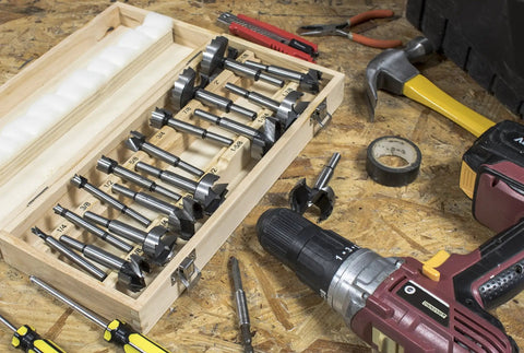 Heavy Duty 16 Piece Forstner Drill Bit Set With Precision Shear Serrated Edges in wooden case with various bits on workbench.