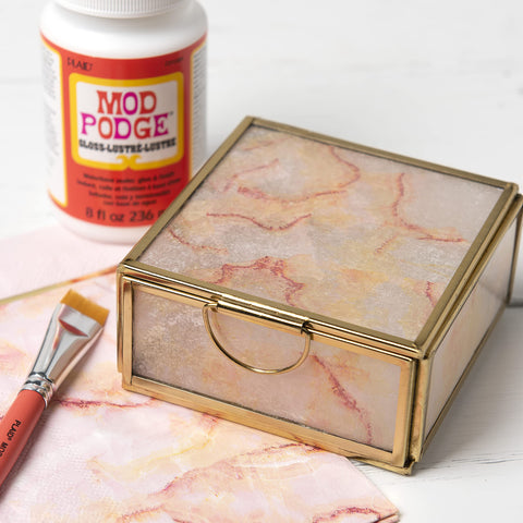 Glass box decorated with paper using All In One Decoupage Glue Sealer And Finish For Wood Paper Fabric Quick Dry Glossy Finish Non Toxic Craft Solution 16 Oz Made In USA Pack Of 1 Great For DIY Projects, with brush and bottle nearby.