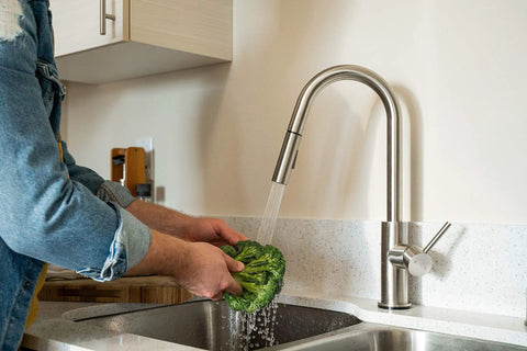 Man washing lettuce under RV Ready Pull Down Kitchen Faucet With One Hand Lever, Detachable Spray Head, And Optional Deck Plate In Brushed Satin Nickel