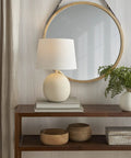 18 Inch Off White Round Metal Table Lamp With Black Cord on wooden console in modern living room setting