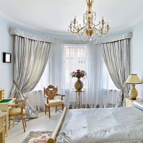 Elegant bedroom with silver drapes and luxurious chandelier hanging from ceiling, featuring Flexible Ceiling Curtain Track System for Ceiling Mount and Room Divider, Sliding Curtain Rail You Can Bend Into Arc, L Shape, Bow Or Trapezoid, Eight Foot Length, Durable Material, No Fuss Setup.