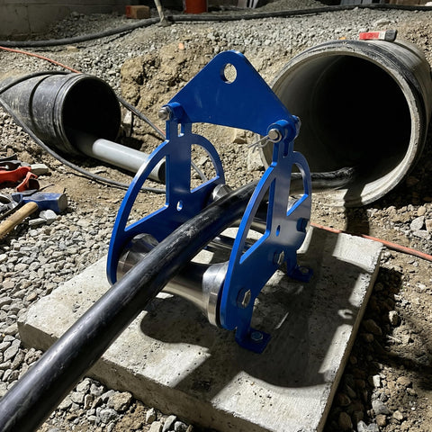 Heavy Duty Cable Puller Sheave For Smooth Wire Rope Pulling And Cable Feeding Industrial Grade Workhorse Wheel With Stainless Steel Rollers On A Blue Powder Coated Steel Frame For Rugged Material Handling in use at a construction site
