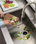 Continuous Feed Garbage Disposal 1/2 HP with 2600+ RPM, Green Finish, disposing mixed vegetable scraps into a kitchen sink