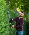 Man using Pro Level 18V ONE PLUS Cordless Hedge Trimmer Featuring 55cm Double Edge Blades trimming a hedge.