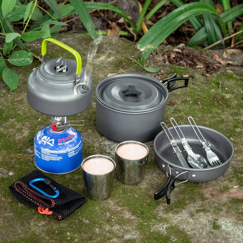 Lightweight Camping Cookware Mess Kit Gear with pot, pan, kettle, two cups, utensils on mossy surface for backpacking, hiking